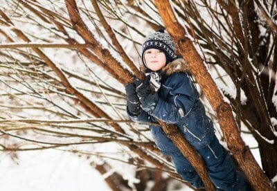 Barn i vinterklær klatrer i et tre