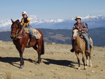 Far og sønn som rir på hester i stekende solskinn i Chile. 