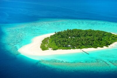 En tropisk øy med hvite sandstrender og turkis vann rundt. 