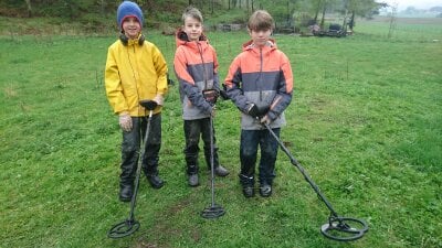 Tre gutter med metalldetektorer står ute i naturen