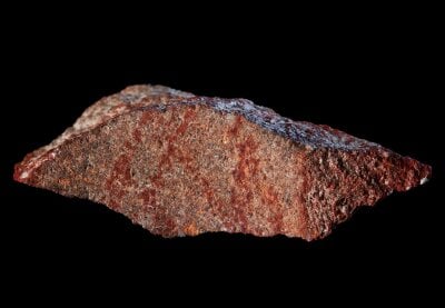 Nærbilde av stein fra blombos-hulen, med røde streker på. .