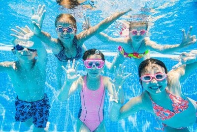 Barn med svømmebriller som dykker i et svømmebasseng