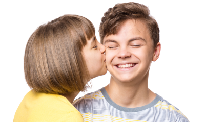 En jente kysser en smilende gutt på kinnet.