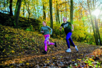 To jenter på løpetur i skogen på høsten.
