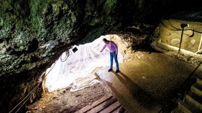 Mann peker på funnsted i hulen Bacho Kiro i Bulgaria