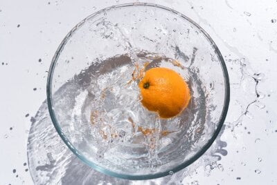 Appelsin faller i en bolle med vann slik at det spruter 