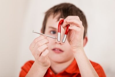 En gutt holder en spiker mot en magnet 