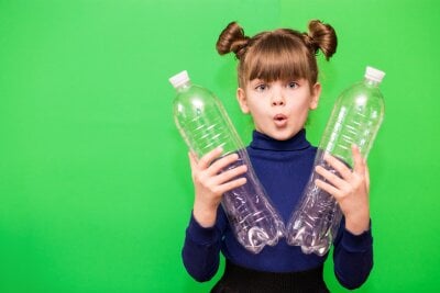 En jente holder opp to tomme vannflasker