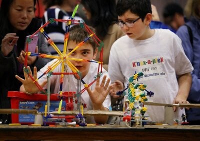 To gutter i 10-års alderen bygger en dominobane i et modellkonstruksjonssystem