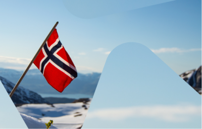 Bilde av et lite norskt flagg som vaier i vinden på toppen av et fjell